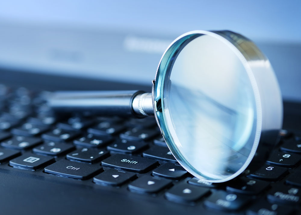 A magnifying glass resting on a computer keyboard, signifying the idea of searching online.