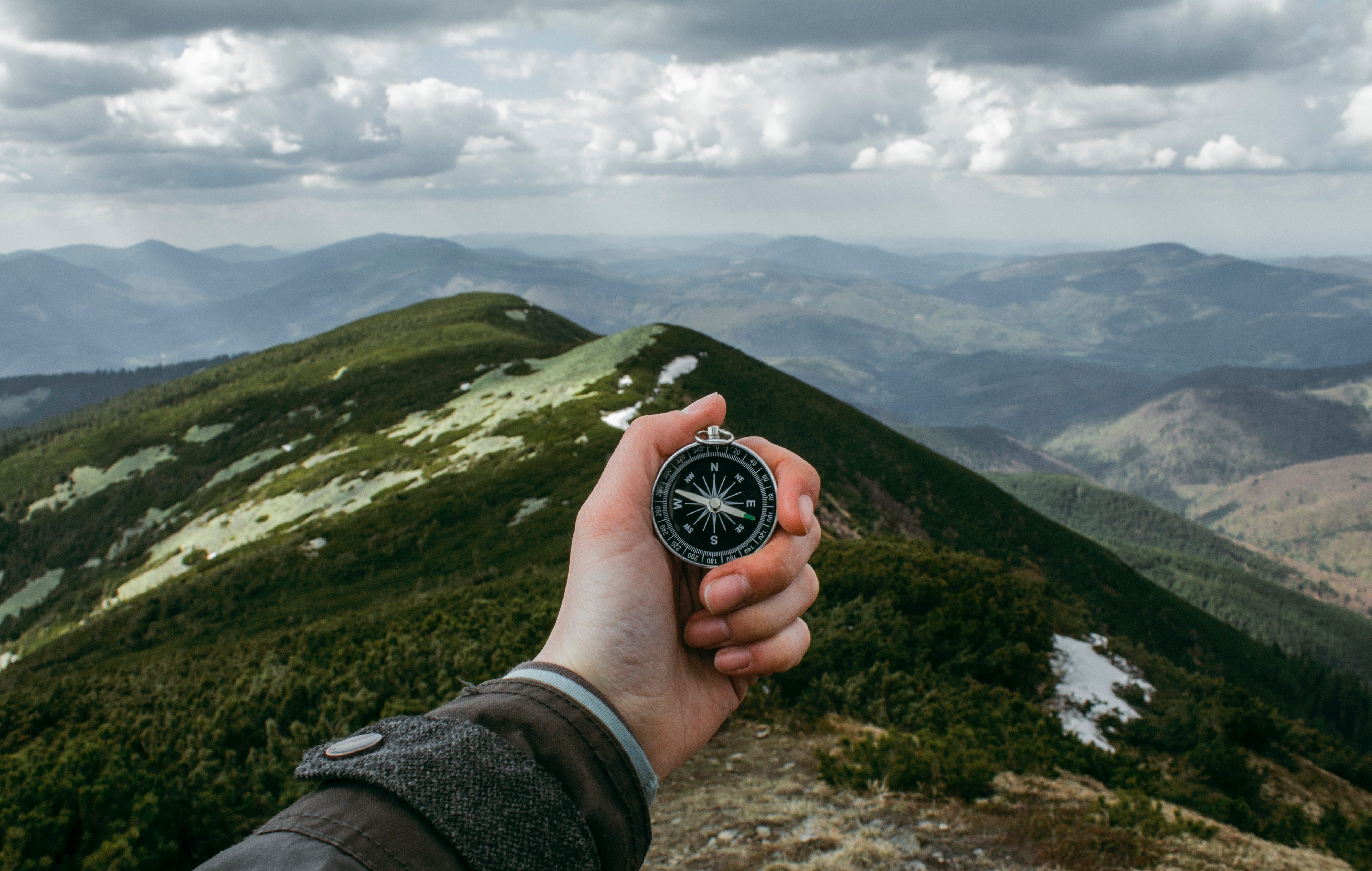 An image of a person holding compass and looking out over mountains